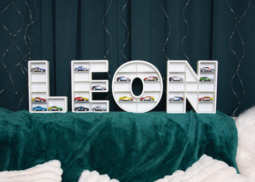 Decorative letters spelling 'LEON' with small car models on a green surface.